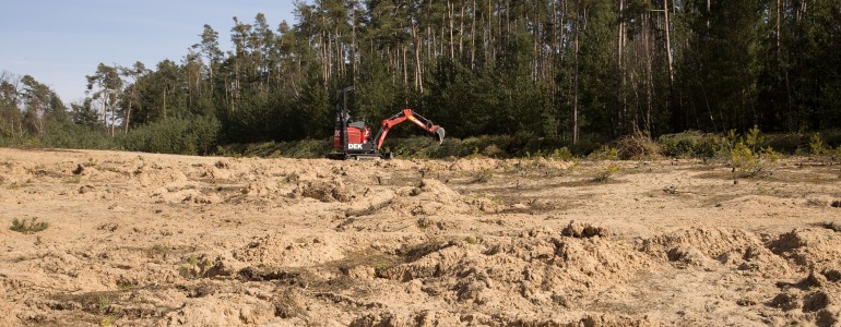 Otevřená písčina s bagrem v pozadí.